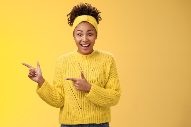 Foto gratuita la joven y entusiasta chica negra milenaria no puede creer que la promoción real amplíe los ojos sonriendo sorprendido ganando increíble oportunidad de billete de lotería apuntando con el dedo índice izquierdo diciéndote una oportunidad genial.