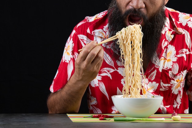 Joven es disfrutar eatting fideos instantáneos en casa.