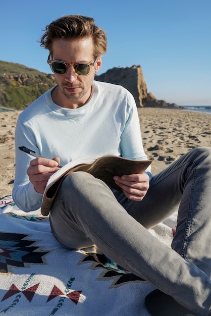 Joven escribiendo en su agenda en la playa