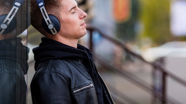 Joven escuchando música en auriculares con espacio de copia