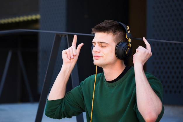 Joven escuchando música en auriculares con las manos levantadas