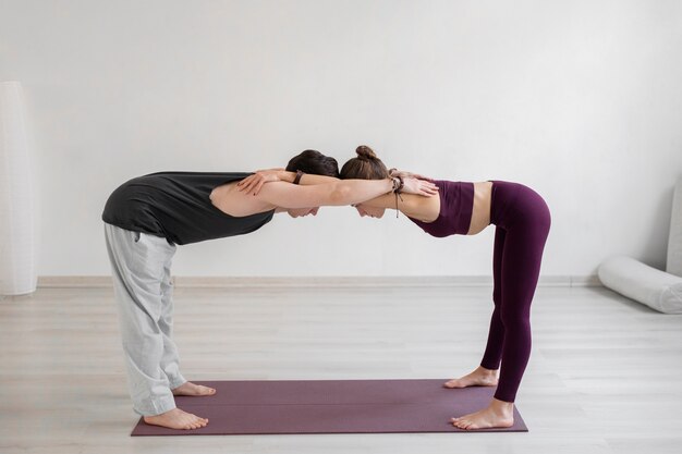 Joven espiritual y mujer practicando yoga en el interior