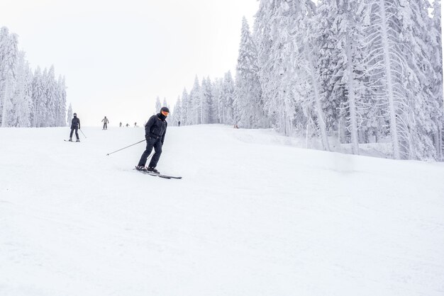 Joven esquiador en movimiento en una estación de esquí de montaña con un hermoso paisaje invernal de fondo