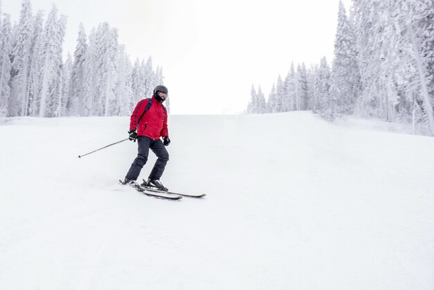 Joven esquiador en movimiento en una estación de esquí de montaña con un hermoso paisaje invernal