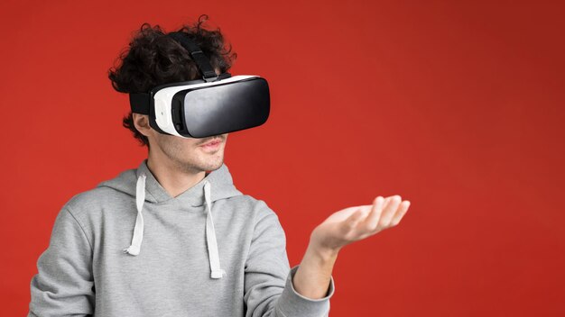 Un joven está jugando juegos usando gafas VR sosteniendo un fondo rojo virtual