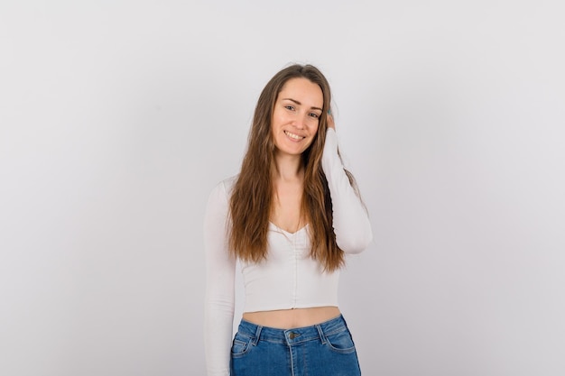 La joven está sonriendo sosteniendo su cabello sobre fondo blanco.