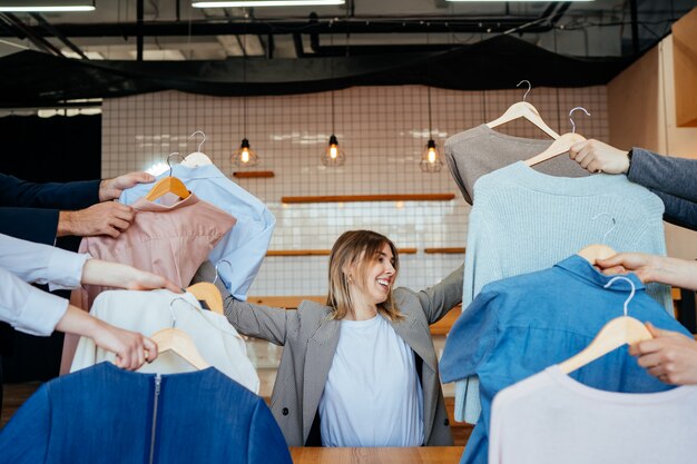 Joven estilista mirando a través de un conjunto de camisas para disparar a la moda