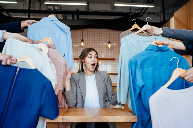 Joven estilista mirando a través de un conjunto de camisas para disparar a la moda