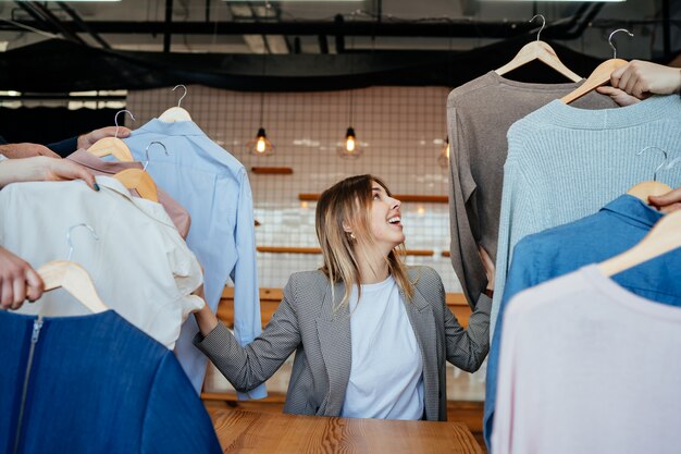 Joven estilista mirando a través de un conjunto de camisas para disparar a la moda