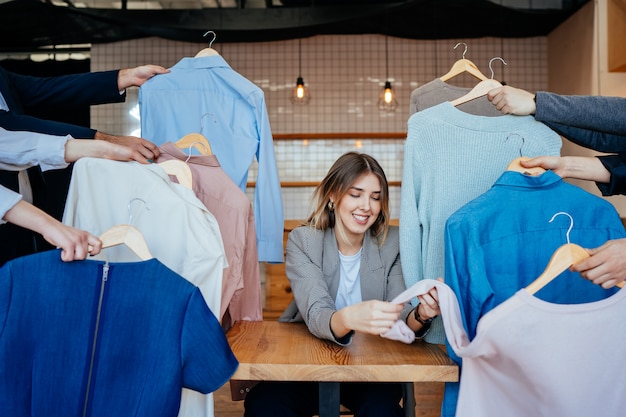 Joven estilista mirando a través de un conjunto de camisas para disparar a la moda