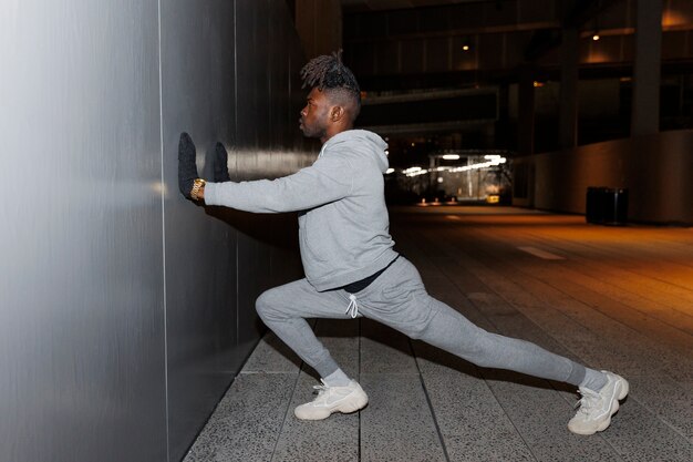 Joven estirando y haciendo ejercicio por la noche en la ciudad