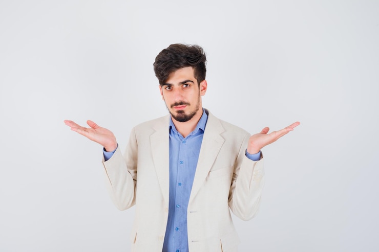 Foto gratuito joven estirando las manos de manera interrogante en camiseta azul y chaqueta de traje blanco y mirando serio