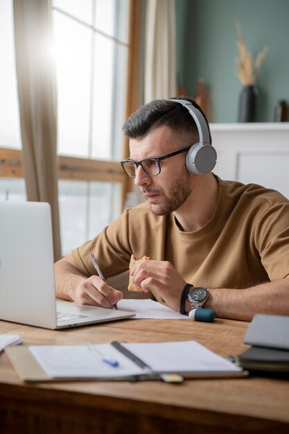 Un joven estudiando en una biblioteca usando una computadora portátil