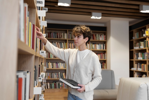 Joven estudiante en busca de un libro en la biblioteca