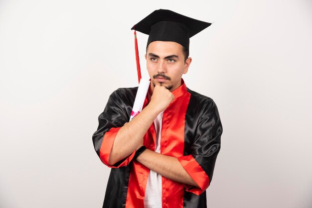 Joven estudiante con diploma pensando en blanco.