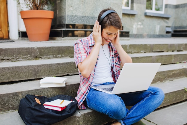Joven estudiante disfrutando de auriculares y portátil