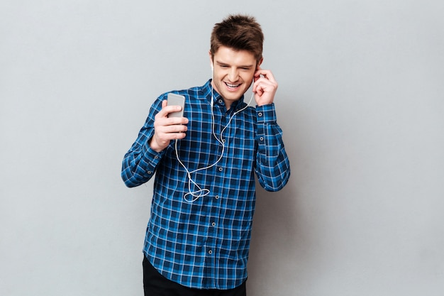 Joven estudiante disfrutando de la música en los auriculares en el teléfono inteligente