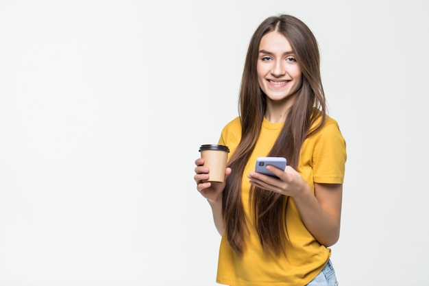 Joven estudiante hermosa chica con teléfono inteligente y café aislado en la pared blanca