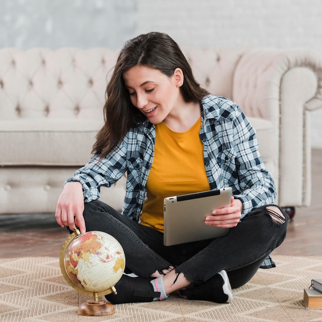 Foto gratuita joven estudiante inteligente usando un globo terráqueo