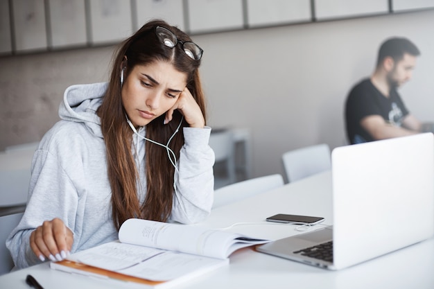 Joven estudiante internacional que aprende un idioma extranjero para solicitar una beca. Chica usando libros de trabajo una computadora portátil para mejorar sus habilidades. Concepto de educación.