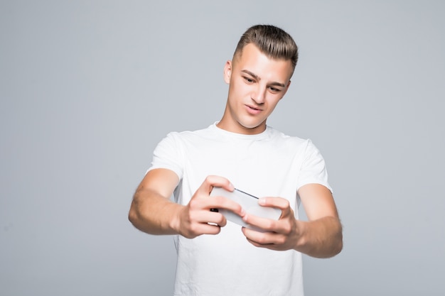 Joven estudiante juega con su teléfono móvil aislado en blanco