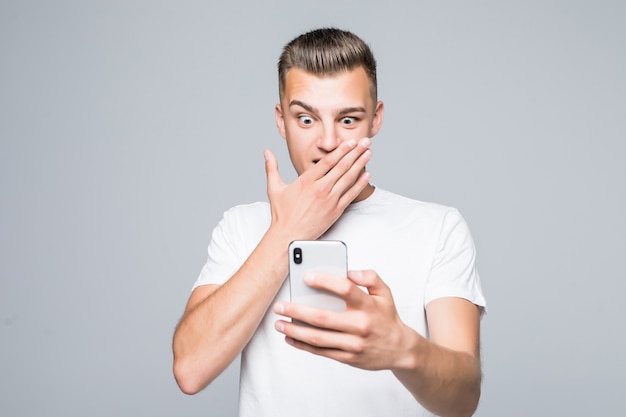 Foto gratuita joven estudiante juega con su teléfono móvil aislado en blanco