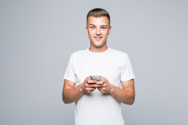 Joven estudiante juega con su teléfono móvil aislado en blanco