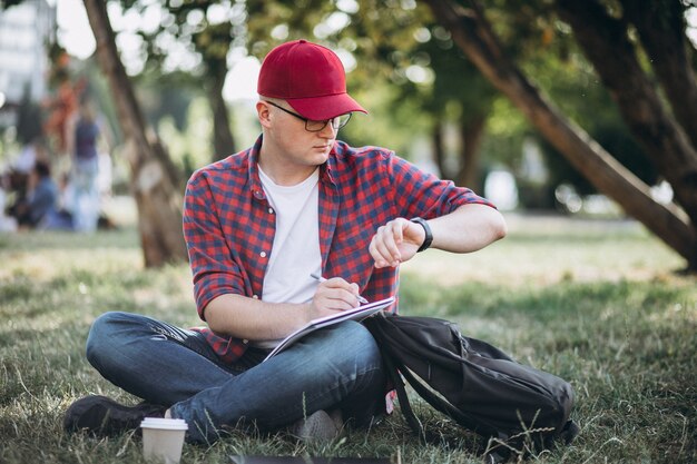 Joven estudiante masculino trabajando en una computadora en el parque