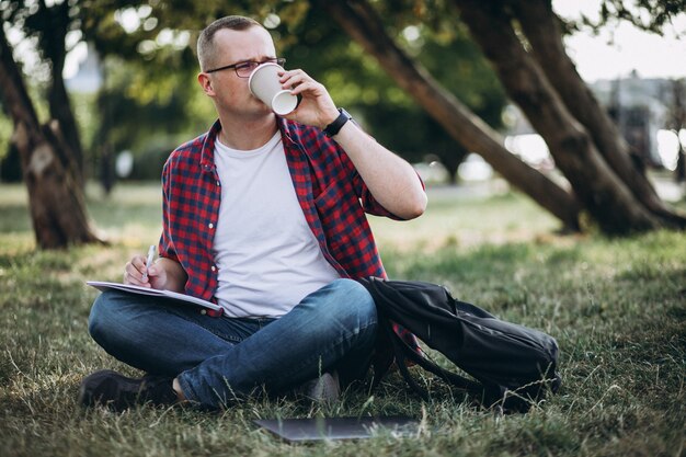 Joven estudiante masculino trabajando en una computadora en el parque