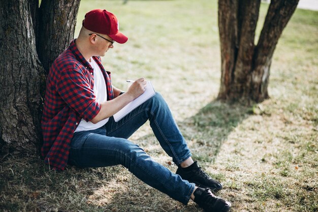 Joven estudiante masculino trabajando en una computadora en el parque