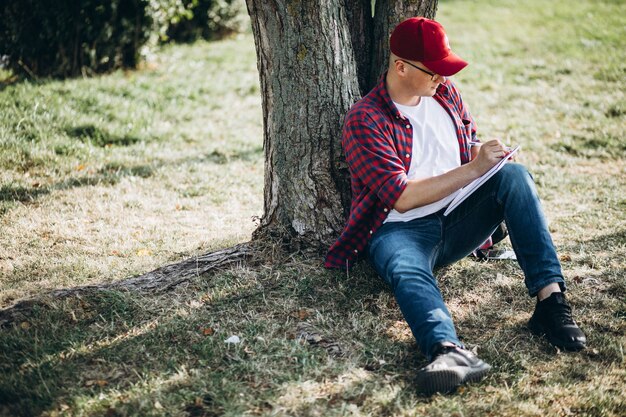 Joven estudiante masculino trabajando en una computadora en el parque