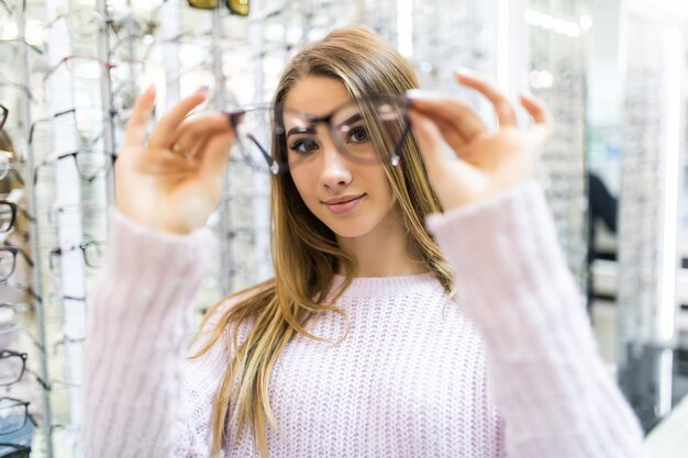 La joven estudiante de moda está preparándose para el estudio universitario y prueba nuevas gafas para su apariencia perfecta en la tienda profesional.