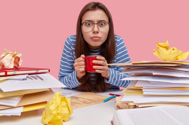 Joven estudiante morena sentada en un escritorio con libros