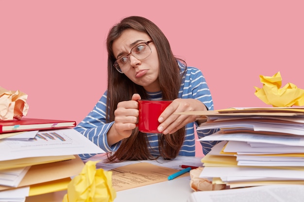 Joven estudiante morena sentada en un escritorio con libros