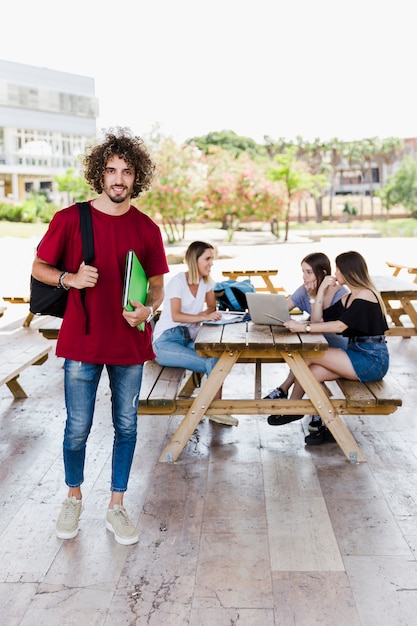 Joven estudiante de pie cerca de amigos