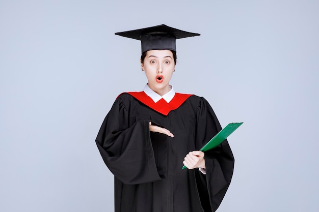 Joven estudiante de posgrado apuntando al diploma. Foto de alta calidad