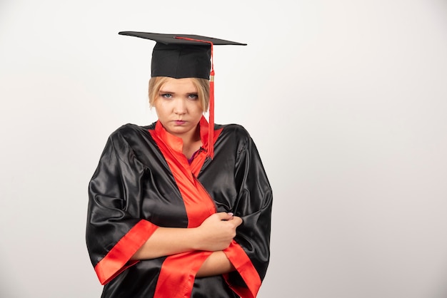 Joven estudiante de posgrado en vestido de pie en blanco.