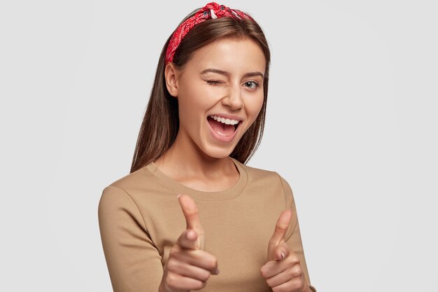 Joven estudiante positivo posando contra la pared blanca