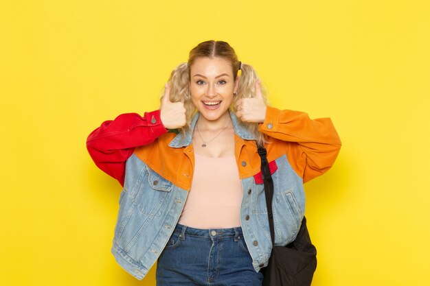 joven estudiante en ropa moderna posando con expresión de deleite en amarillo