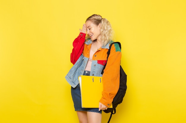 Joven estudiante en ropa moderna simplemente posando con una sonrisa en amarillo