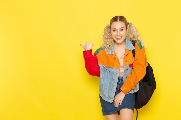 Joven estudiante en ropa moderna simplemente posando con una sonrisa señalando en amarillo