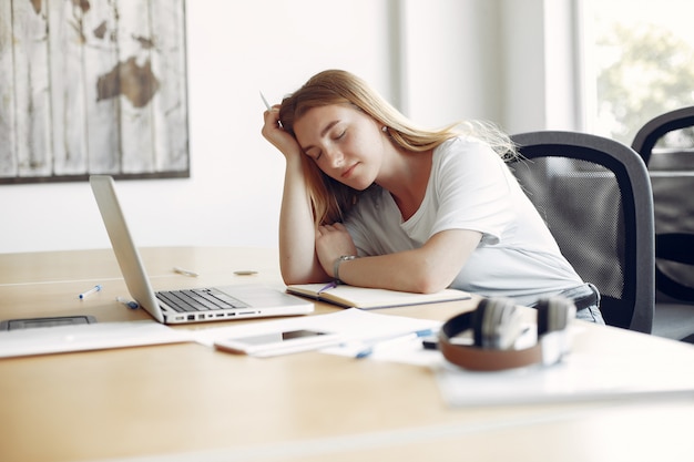 Foto gratuita joven estudiante sentada en la mesa y durmiendo