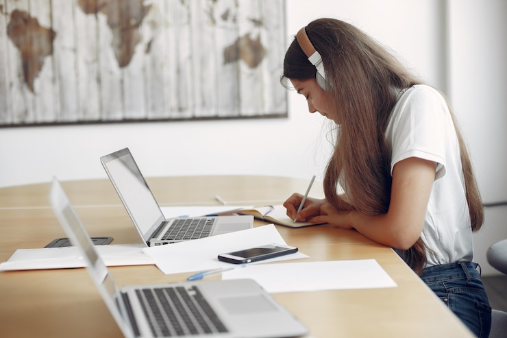 Foto gratuito joven estudiante sentado en la mesa y usando la computadora portátil