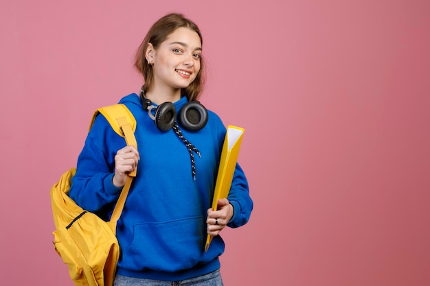 Joven estudiante sosteniendo mochila amarilla y carpeta sonriendo