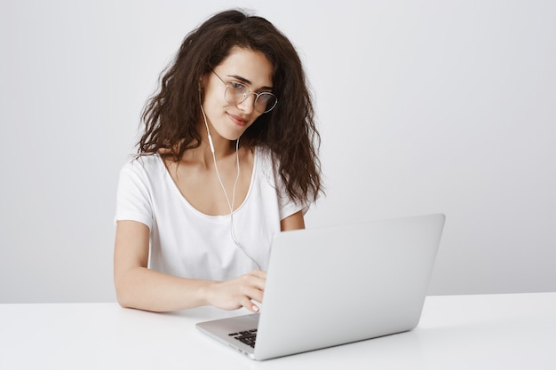Joven estudiante trabajando con un portátil, sonriendo a la pantalla