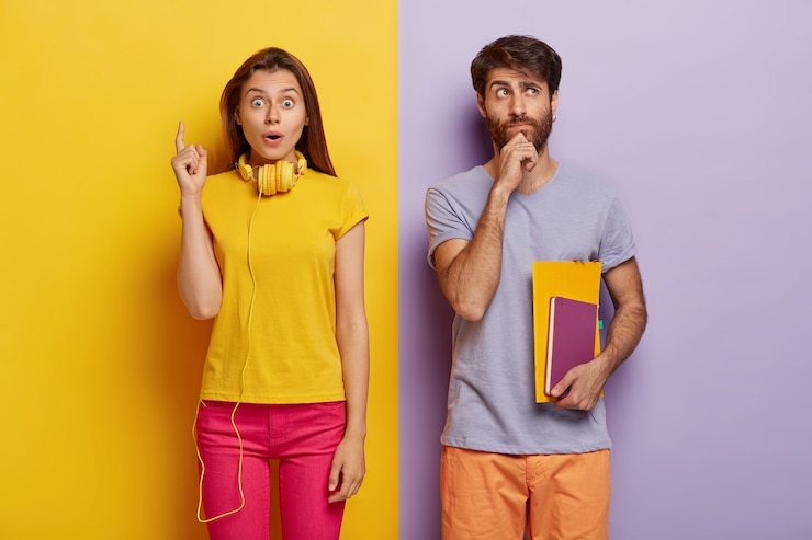 Foto gratuito un joven europeo pensativo sostiene la barbilla, sostiene un cuaderno y un libro de texto, piensa en una lección creativa, una mujer impresionada en ropa casual, señala con el dedo índice hacia arriba, tiene una idea inesperada