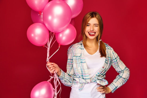 Joven excitada posando con globos rosados