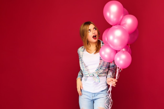 Joven excitada posando con globos rosados