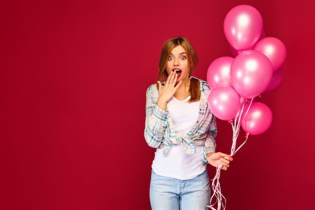 Joven excitada posando con globos rosados