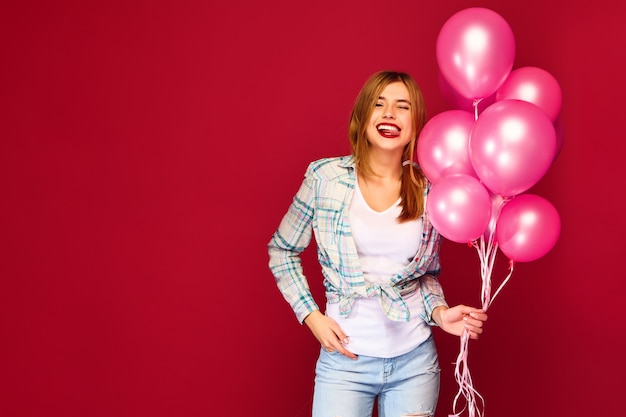 Foto gratuita joven excitada posando con globos rosados